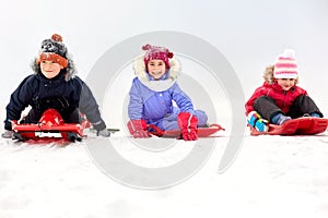 Happy little kids sliding down on sleds in winter