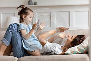 Happy little preschool girl playing patty cake with mom.