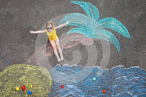 Happy little preschool girl in swimsuit on inflatable ring with sea, sand, palm painted with colorful chalks on asphalt. Cute