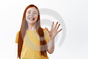 Happy little redhead kid, girl child show five fingers number and laughing, smiling broadly, standing over white
