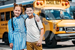 happy little scholars embracing and looking at camera in front of