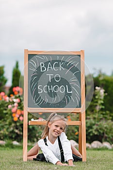 Happy little schoolgirl with a chalkboard outdoor