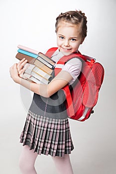 Happy little schoolgirl in uniform standing on white background