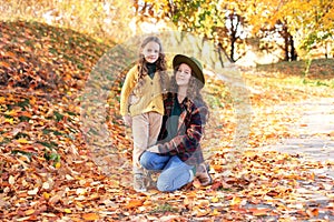 Happy little sisters hugging on an autumn background for halloween. A smiling girlfriends walking in fall park.