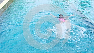 Happy little sisters are swimming and playing in outdoor swimming pool in a tropical resort during family summer vacation. Kids le