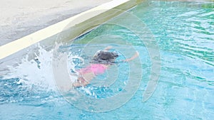 Happy little sisters are swimming and playing in outdoor swimming pool in a tropical resort during family summer vacation. Kids le
