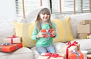 Happy little smiling girl with christmas gift box at living room