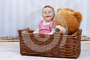 Happy little toddler in the basket with teddy bear