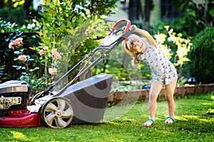 Happy little toddler girl with lawn mower. Preschool child cut the lawn and help the family. Portrait of toddler working