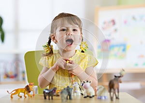 Happy little toddler plays animal toys at home or daycare centre