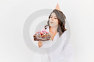 a happy lonely woman with a birthday cake with candles on a white background