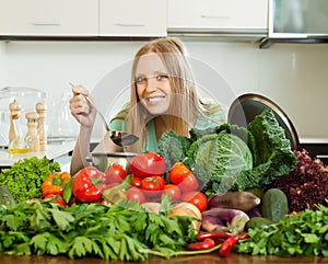 Happy long-haired woman cooking with heap of vegetables