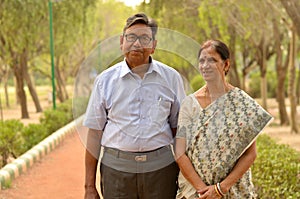 Happy looking retired senior Indian man and woman couple smiling and posing in a park outdoor setting in New Delhi, India. Concept