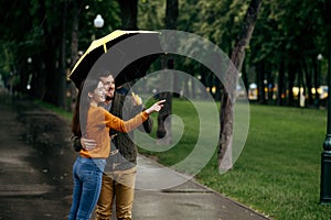 Happy love couple leisures in park, rainy day