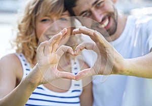 Happy love couple outside showing heart with fingers