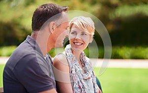 Happy, love and couple in a park with conversation, chat or romantic bonding in nature together. Smile, trust and people