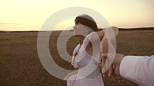 Happy in love couple runs hand in hand. girl runs across the field holding the hand of her beloved man and laughs. Slow
