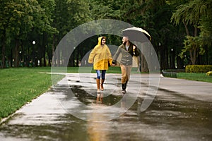 Happy love couple runs in park, summer rainy day