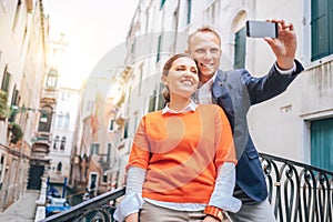 Happy in love couple take selfie photo on one of numerous bridge in Venice, Italy. Traveling to