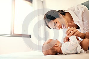 Happy, love and a mother with her baby in the bedroom of their home together for playful bonding. Family, children and a