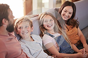 Happy, love and parents on a sofa with their children talking, laughing and bonding in the living room. Happiness, smile