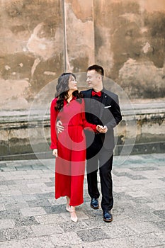 Happy and lovely Asian couple of bride and groom in the background of the old town city. Woman in red dress and man in