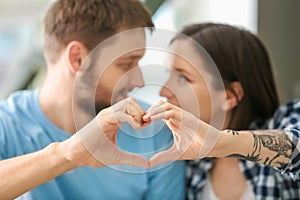 Happy lovely couple making heart with their hands, closeup