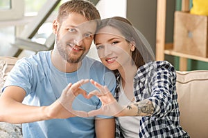 Happy lovely couple making heart with their hands at home