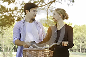 Happy lovely young couple with bike walking in the garden  spending time together. Lover going on a picnic in summer park and