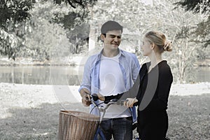 Happy lovely young couple with bike walking in the garden  spending time together. Lover going on a picnic in summer park and