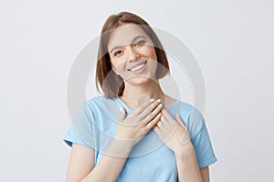 Happy lovely young woman in blue t shirt put hands on her heart area and smiling isolated over white background Fall in love