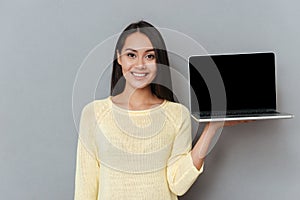 Happy lovely young woman holding blank screen laptop