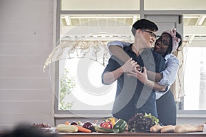 Happy lover with smiling young black woman hug young asian man in kitchen room