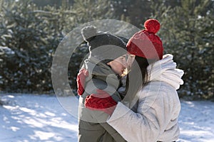 Happy lovers embrance in winter forest. Young couple in love walking outside