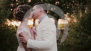 Happy lovers kiss at sunset in very picturesque place on wedding day. Beautiful view of lovers in nature. Side view