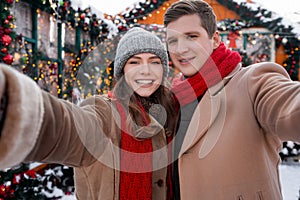 Happy lovers taking selfie while spending winter holidays at backyard