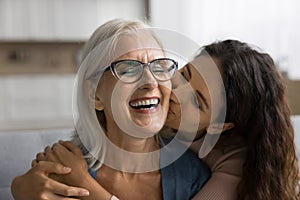 Happy loving adult daughter kissing cheerful laughing mature mum
