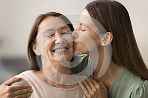 Happy loving adult daughter woman hugging and kissing senior mom