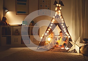 Happy loving children brother and sister play in dark tent in playroom at home