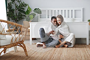 Happy loving couple drinking cocoa on winter morning in bed