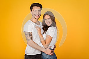 Happy loving couple embracing against yellow background