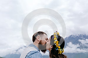 Happy loving couple embracing and kissing outdoors at summertime under blue sky.