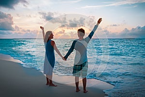 Happy loving couple enjoy sunset beach, family hands up at sky