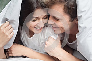 Happy loving couple enjoying romantic moment under blanket