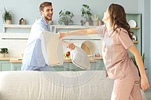 Happy loving couple having fun while having a pillow fight in the living room