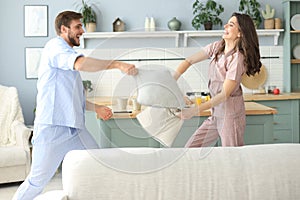 Happy loving couple having fun while having a pillow fight in the living room