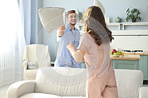 Happy loving couple having fun while having a pillow fight in the living room