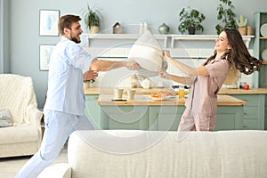 Happy loving couple having fun while having a pillow fight in the living room