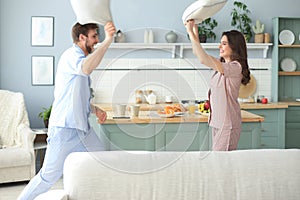 Happy loving couple having fun while having a pillow fight in the living room