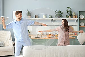 Happy loving couple having fun while having a pillow fight in the living room